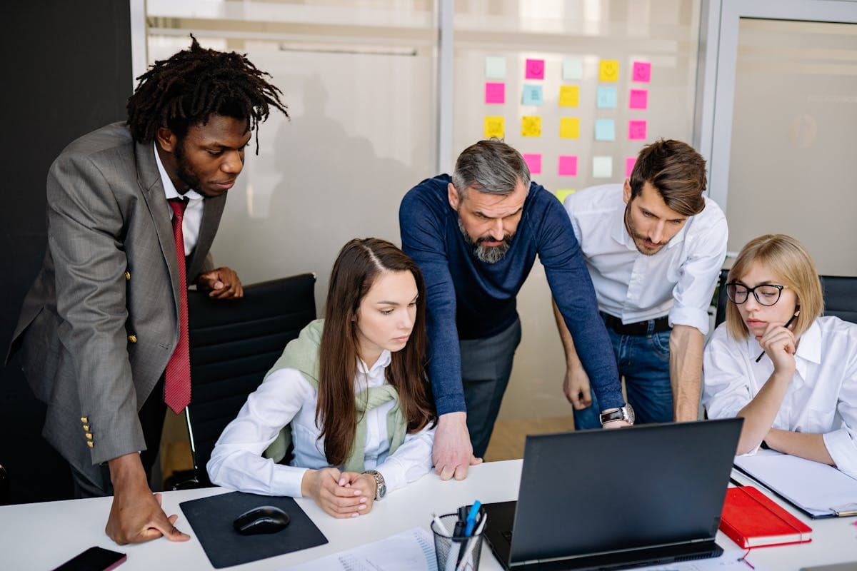 A business team gathered around a laptop during an internal coordination session.